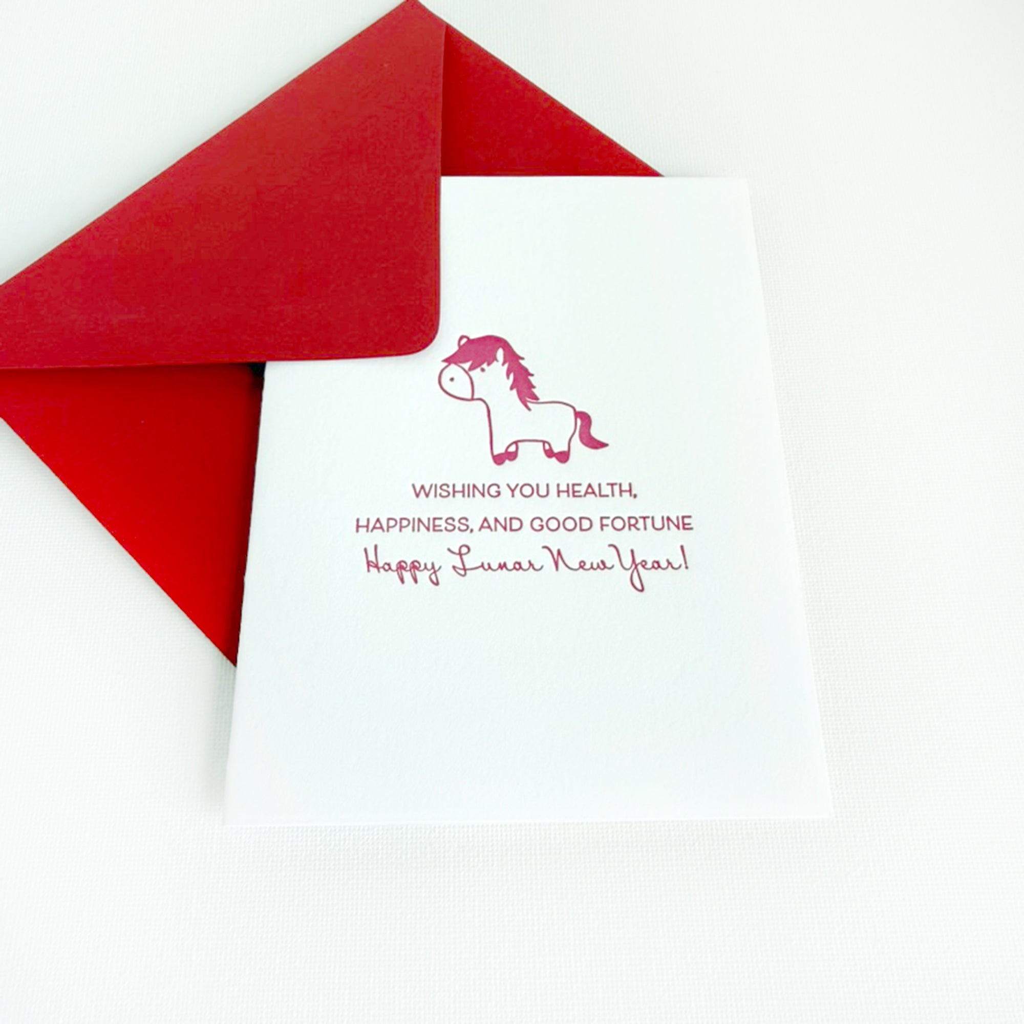 Red envelope with a white card featuring a horse illustration and lunar new year wishes on a white background