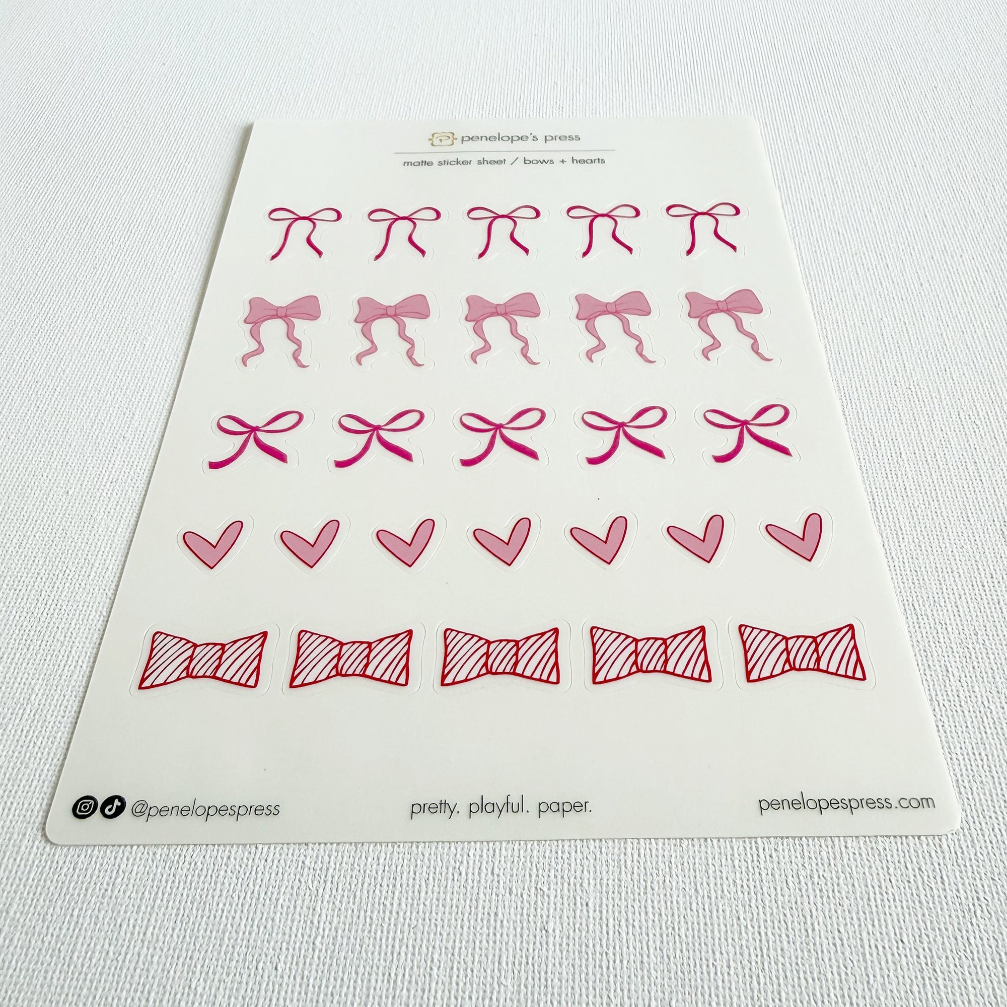 Sheet of decorative stickers with pink bows and hearts on a white background