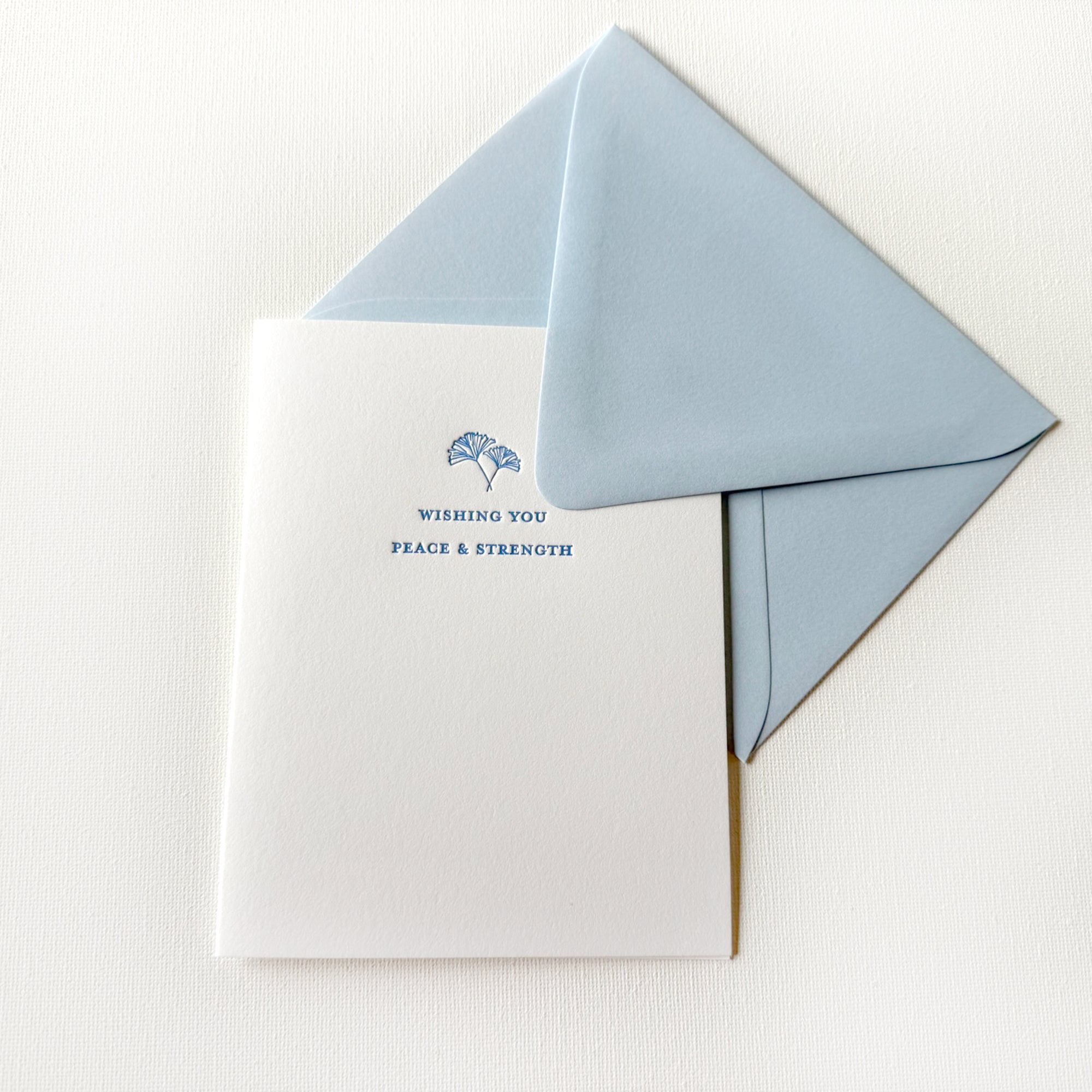 letterpess card with blue text that says "wishing you peace & strength" with hand drawn ginkgo leaves and blue envelope on white cardstock

letterpress sympathy and condolence card

wishing you peace and strength card